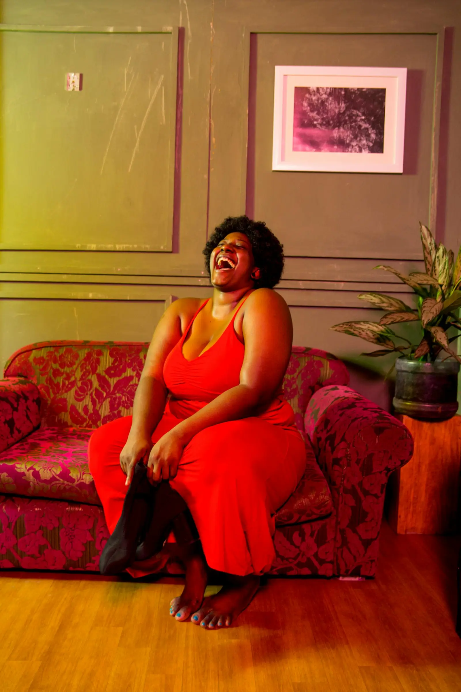 Black woman relaxing on a sofa at home with an expression of joy and relief after good news
