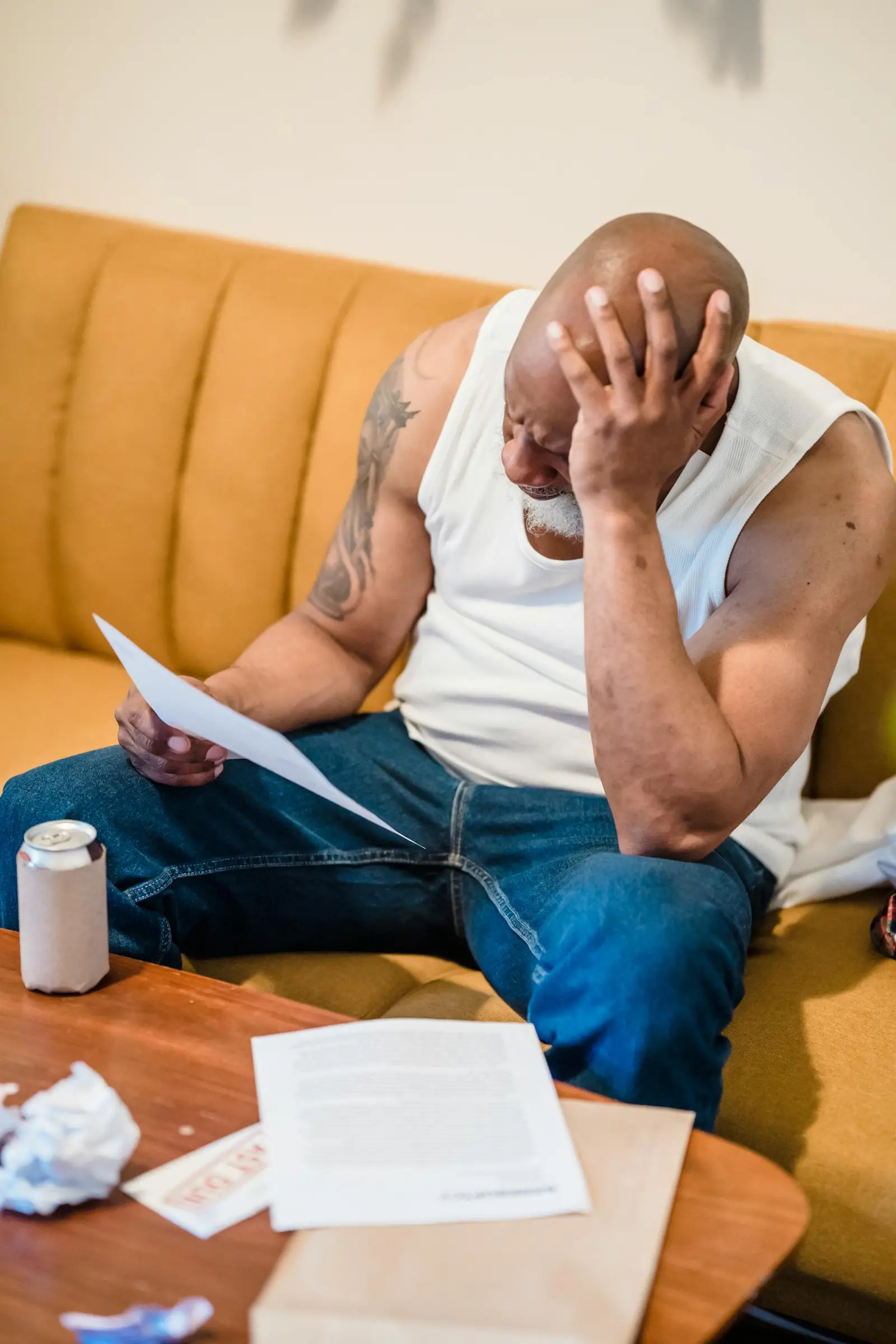 A man in his 60s reviewing Social Security paperwork and past-due notices at his living room table